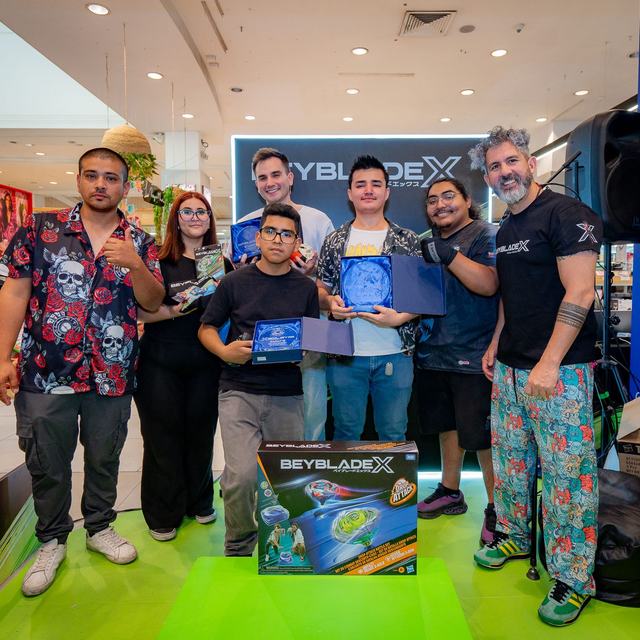 Equipo y participantes del torneo Beyblade X posando con sus premios en un mall
